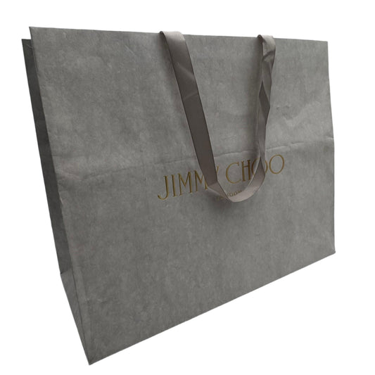 Gray shopping bag with 'Jimmy Choo' branding on a white surface.