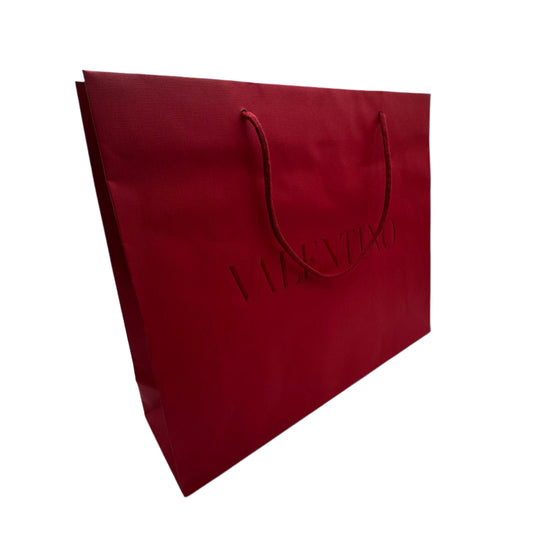 Red paper bag on a white surface with a textured wall background