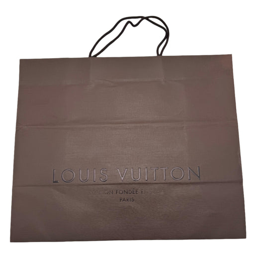 Brown Louis Vuitton shopping bag on a white surface