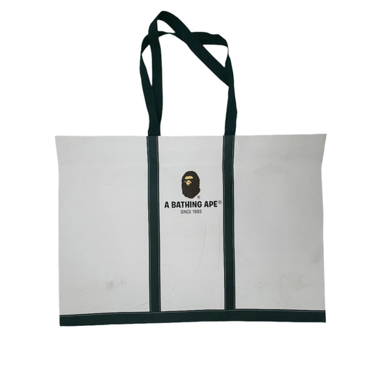 White tote bag with green strap and brand logo on a white background