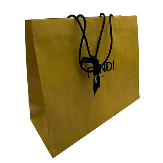 Gold paper bag with black handle and logo on a white background