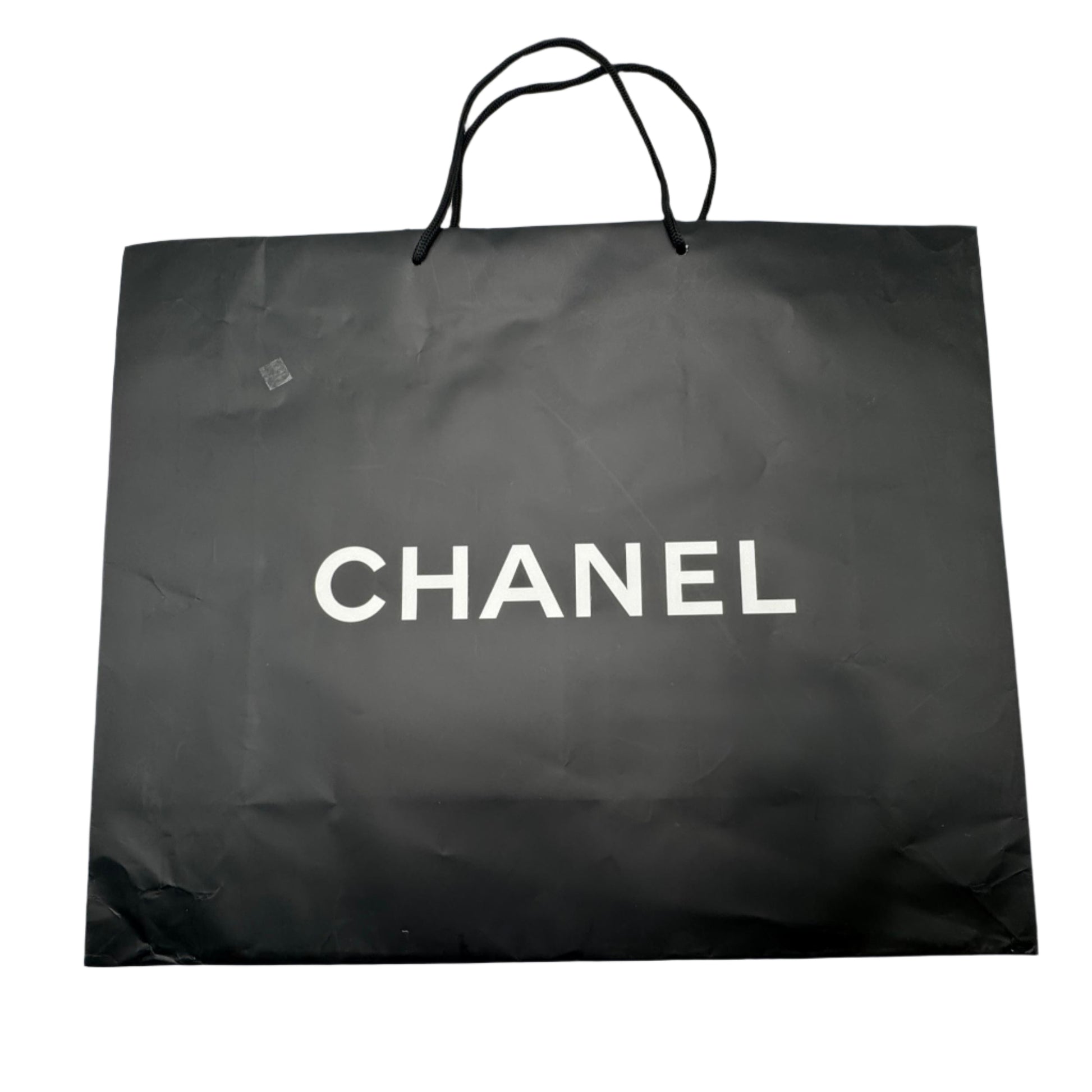 Black Chanel shopping bag on a white surface