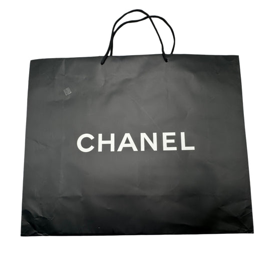 Black Chanel shopping bag on a white surface